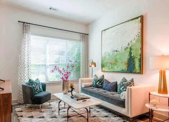 A living room with a couch, chair, and a painting on the wall.