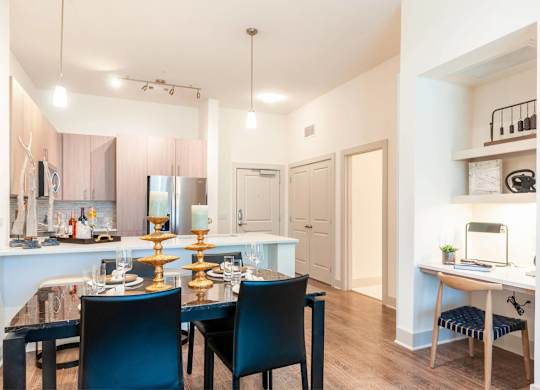 A dining room with a table set for two and a kitchen area in the background.