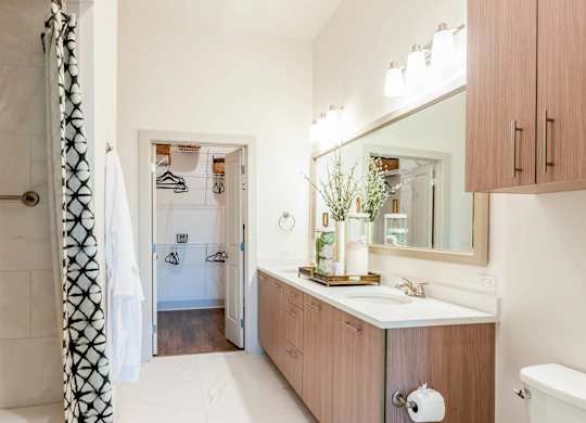 A bathroom with a white tub, wooden cabinets, and a large mirror.