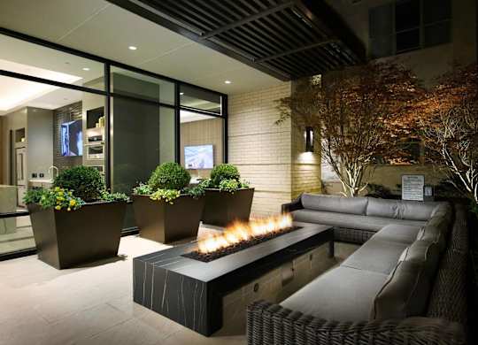 A modern outdoor seating area with a fire pit and comfortable couches.