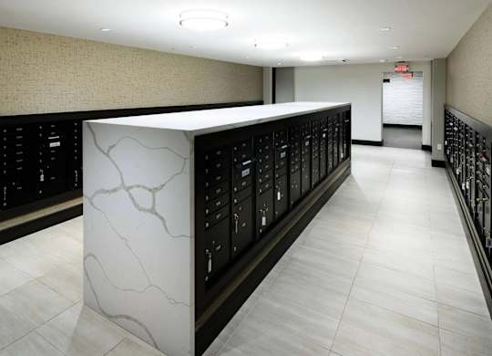 A long hallway with a white marble pillar and black lockers on the side.