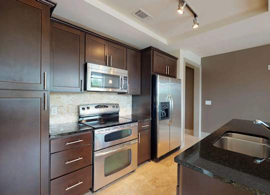 A kitchen with dark brown cabinets and stainless steel appliances.