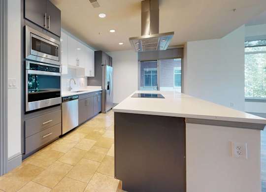 A modern kitchen with a large island and stainless steel appliances.
