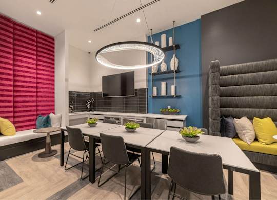 A modern dining room with a long table and grey chairs.