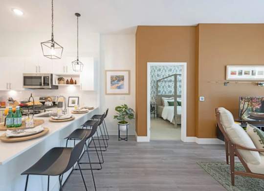 A kitchen with white countertops and black chairs.