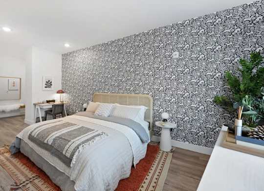 A bedroom with a large bed and a patterned wallpaper.