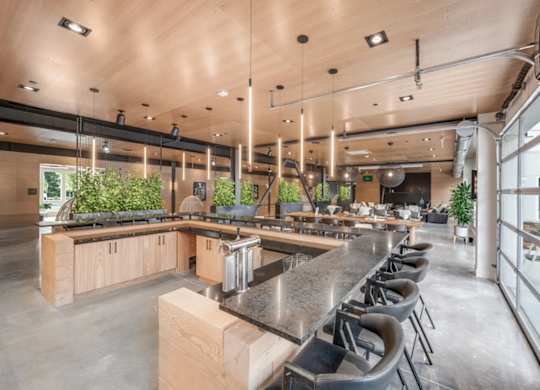 A modern kitchen with a long counter and bar stools.