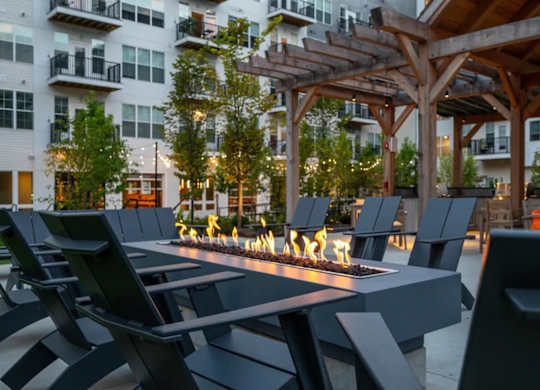 A patio with chairs and a fire pit in front of a building.