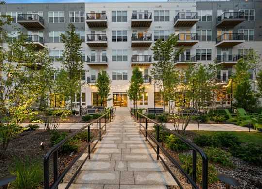 A walkway leads to a building with balconies.