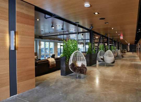 A long hallway with hanging plants and a bench.