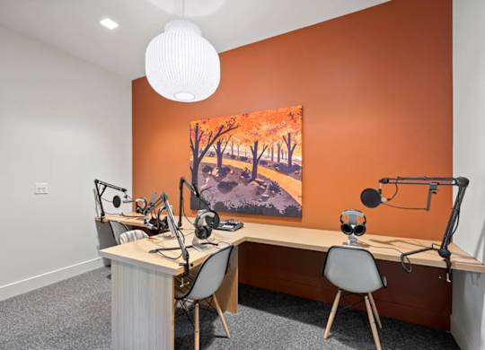 A room with orange walls and a painting of a tree-lined path.