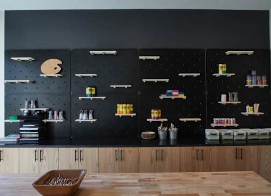 A room with a black wall and shelves filled with books and other items.