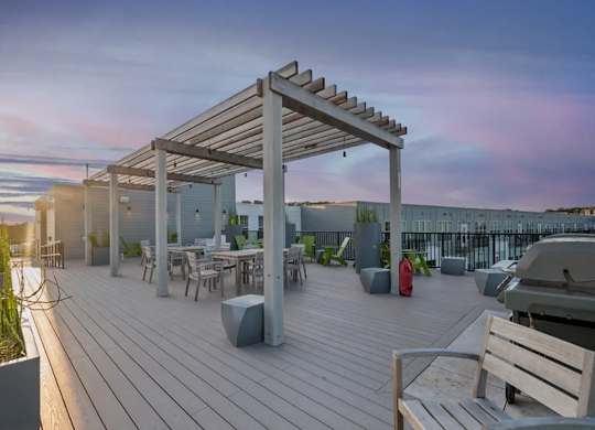 A wooden deck with a pergola and seating area overlooking a body of water.