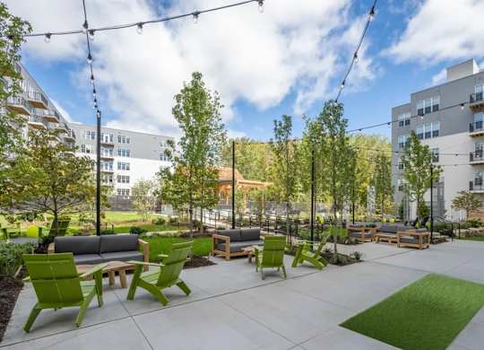 A modern outdoor seating area with green chairs and benches.