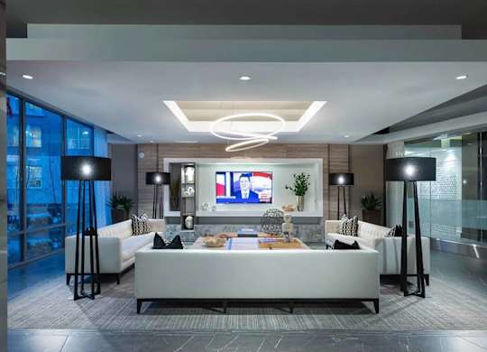 A modern living room with a white sofa and a television displaying a news channel.