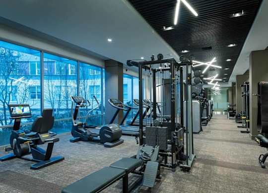 A gym with a variety of equipment including treadmills, weights, and exercise machines.