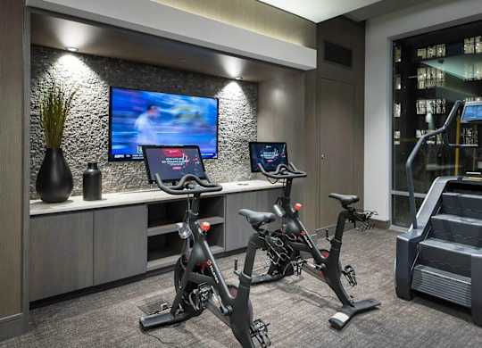 A modern gym with exercise bikes and a television.