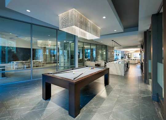 A pool table is in the middle of a room with a glass wall.