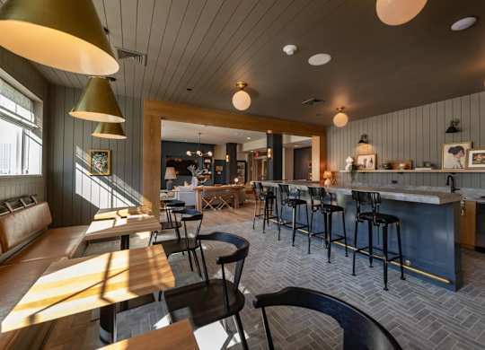 A modern kitchen and dining area with a bar and stools.