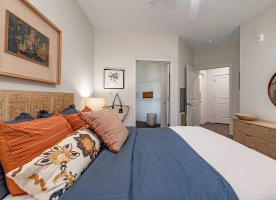 A bedroom with a bed, a mirror, and a painting on the wall.