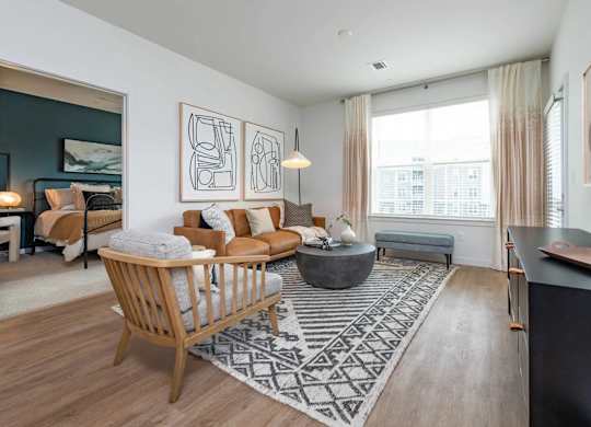 A living room with a large window, a sofa, a chair, and a rug.