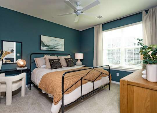 A bedroom with a bed, a side table, and a ceiling fan.