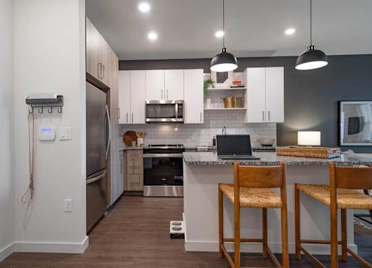A kitchen with a refrigerator, stove, and bar stools.
