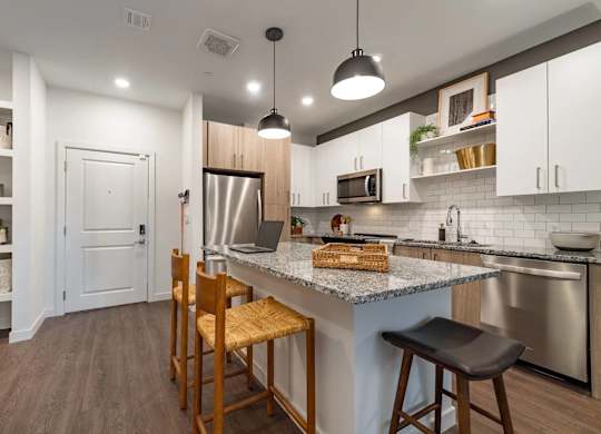 A kitchen with a white counter top and wooden chairs.