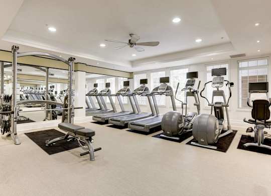 A spacious gym with a variety of equipment including treadmills, elliptical machines, and weight machines.