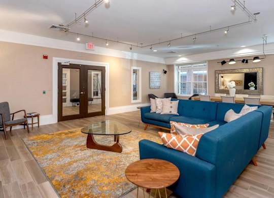 A blue couch with a glass table in front of it.