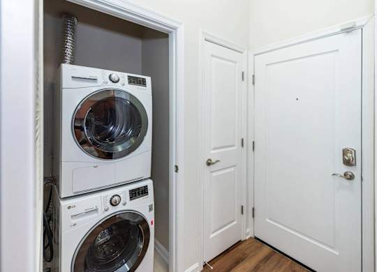 A white door is open to a laundry room with two washing machines.