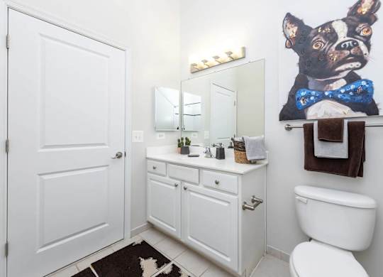 A white bathroom with a dog picture on the wall.
