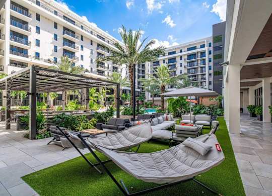 A patio with chairs and a table is surrounded by buildings.