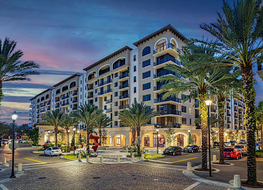 A large hotel with a parking lot in front of it.