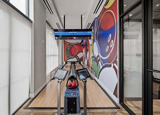 A bowling alley with a row of lanes and a colorful mural on the wall.
