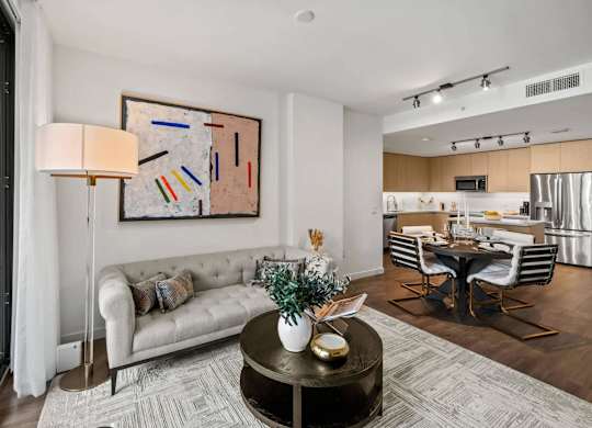 A modern living room with a white sofa, a coffee table, and a painting on the wall.