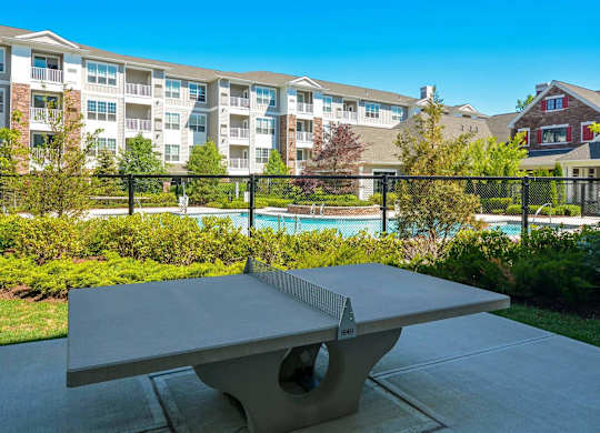 A table tennis table is in the foreground of a residential area with apartment buildings in the background.