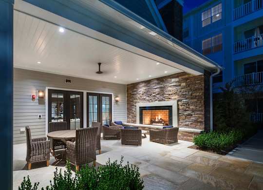 A patio with a table and chairs is lit up at night.