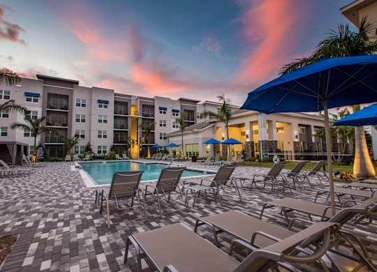A sunny day at the pool with chairs and umbrellas.