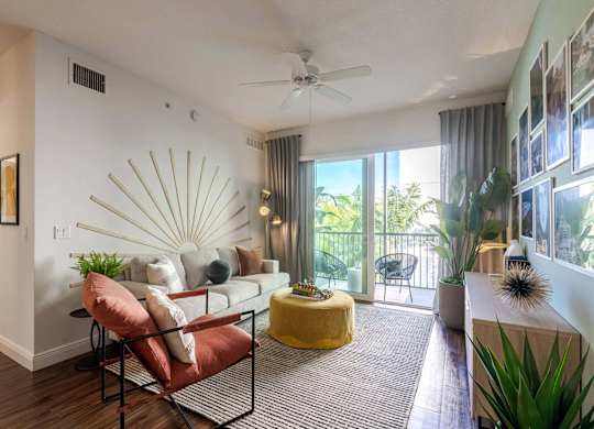 A living room with a yellow ottoman and a red chair.