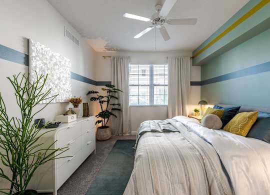 A bedroom with a large bed and a ceiling fan.
