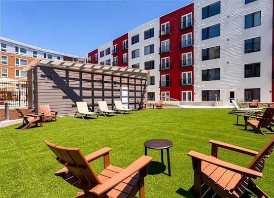 A sunny day at a grassy courtyard with wooden chairs and tables.