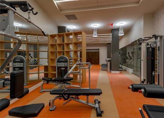 A gym with orange flooring and various exercise equipment.
