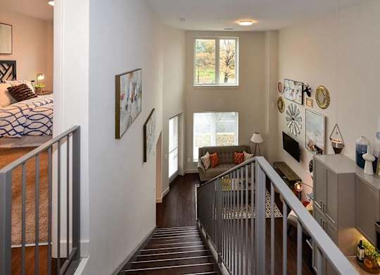 A hallway with a staircase and a bedroom at the end.