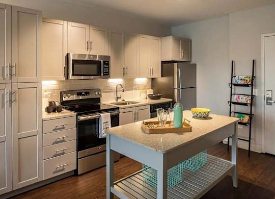 A kitchen with a stove, refrigerator, and microwave.