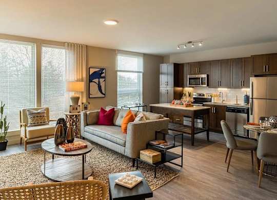 A modern living room with a grey sofa, a coffee table, and a dining table with chairs.