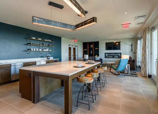 A modern kitchen with a long island and a blue chair.