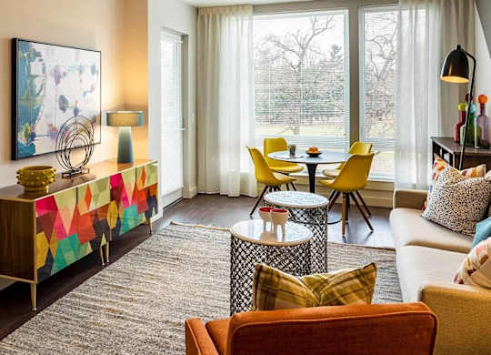 A living room with a yellow chair and a grey rug.