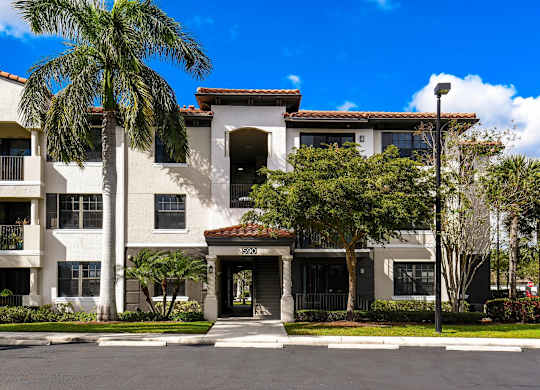 A building with a red tile roof and a palm tree in front.