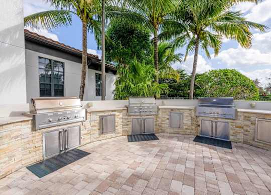 A patio with a stone wall and four grills.